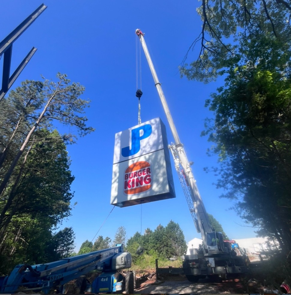 Crane lifting a Burger King roadside sign during a sign installation job