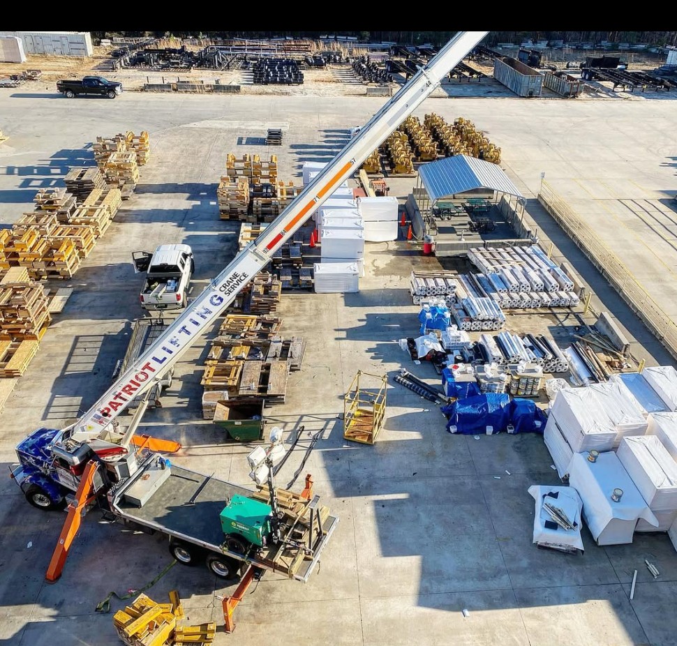 Aerial view of a Patriot Lifting branded crane in an industrial yard surrounded by pallets and steel