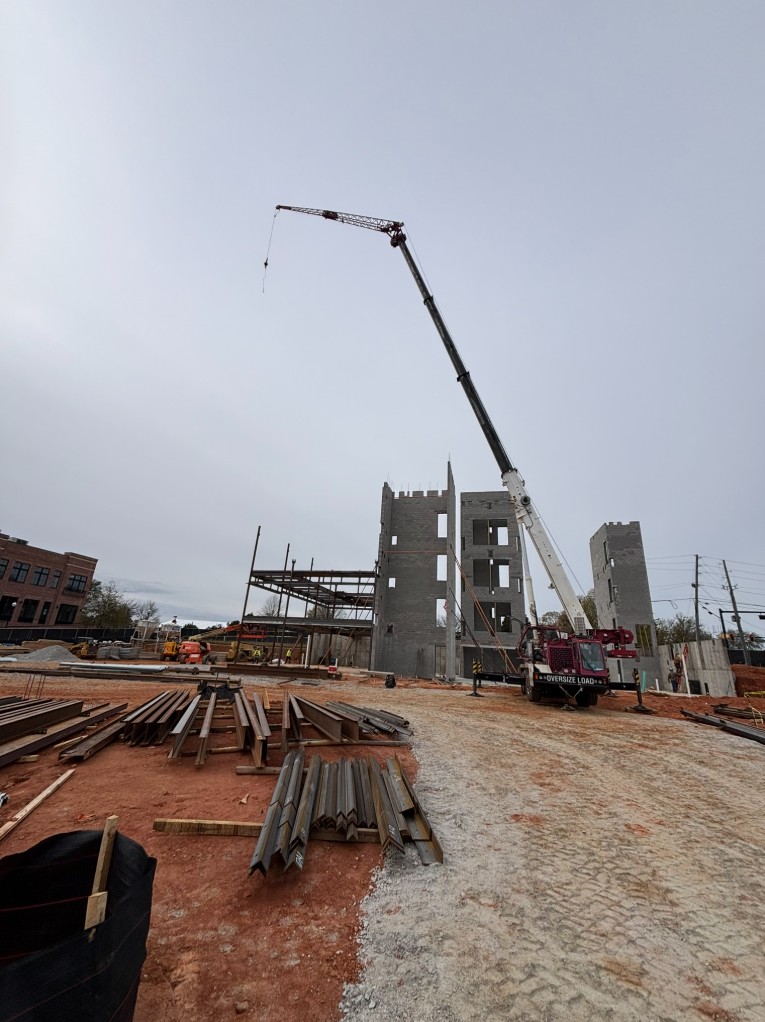 Red crane working at an institutional stone building construction site