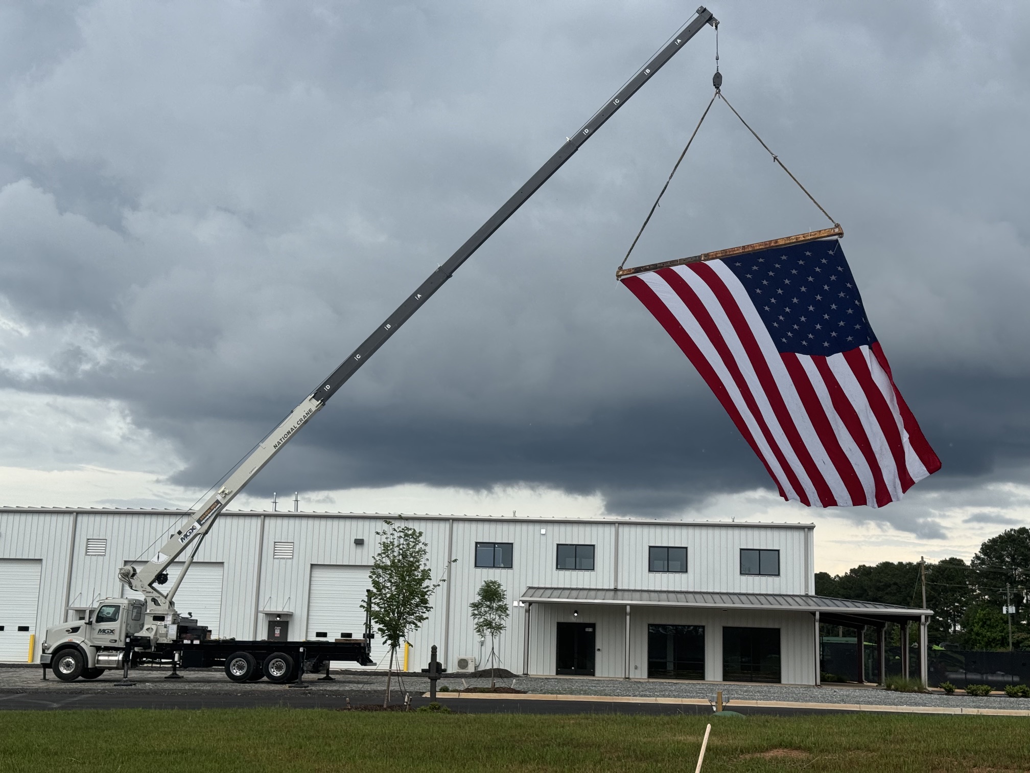 Wider view of Patriot Lifting boom crane flying an American flag with dramatic clouds in the background
