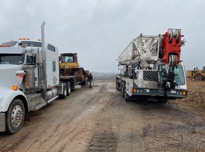 Patriot Lifting Grove crane and white Peterbilt staging a Caterpillar dozer for transport