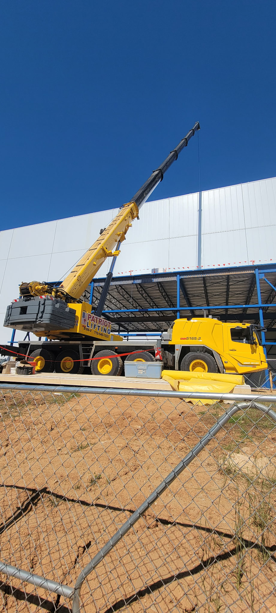 Yellow Volvo crane positioned at the exterior of an industrial warehouse