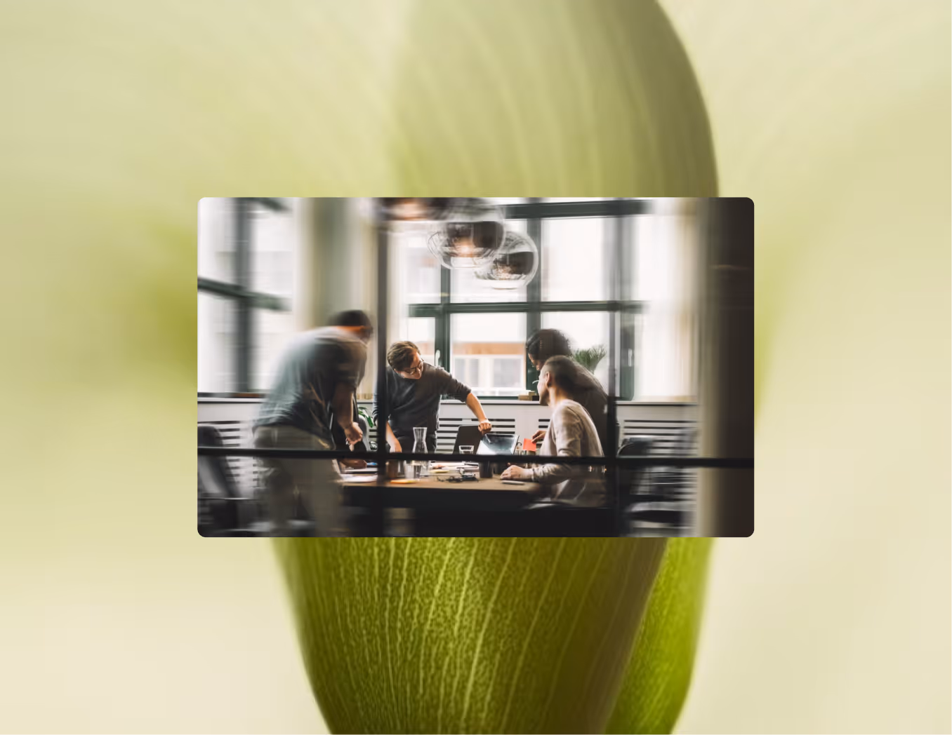 Four people working together around a table in a modern office with large windows.