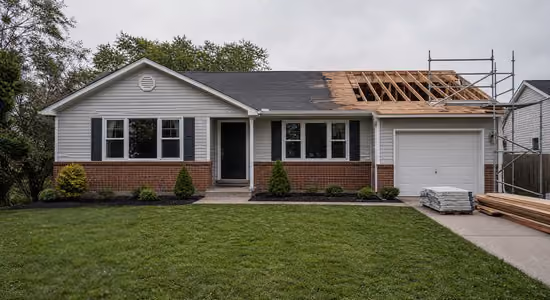 Single-story house with partially removed roof and scaffolding for roof repair or replacement.