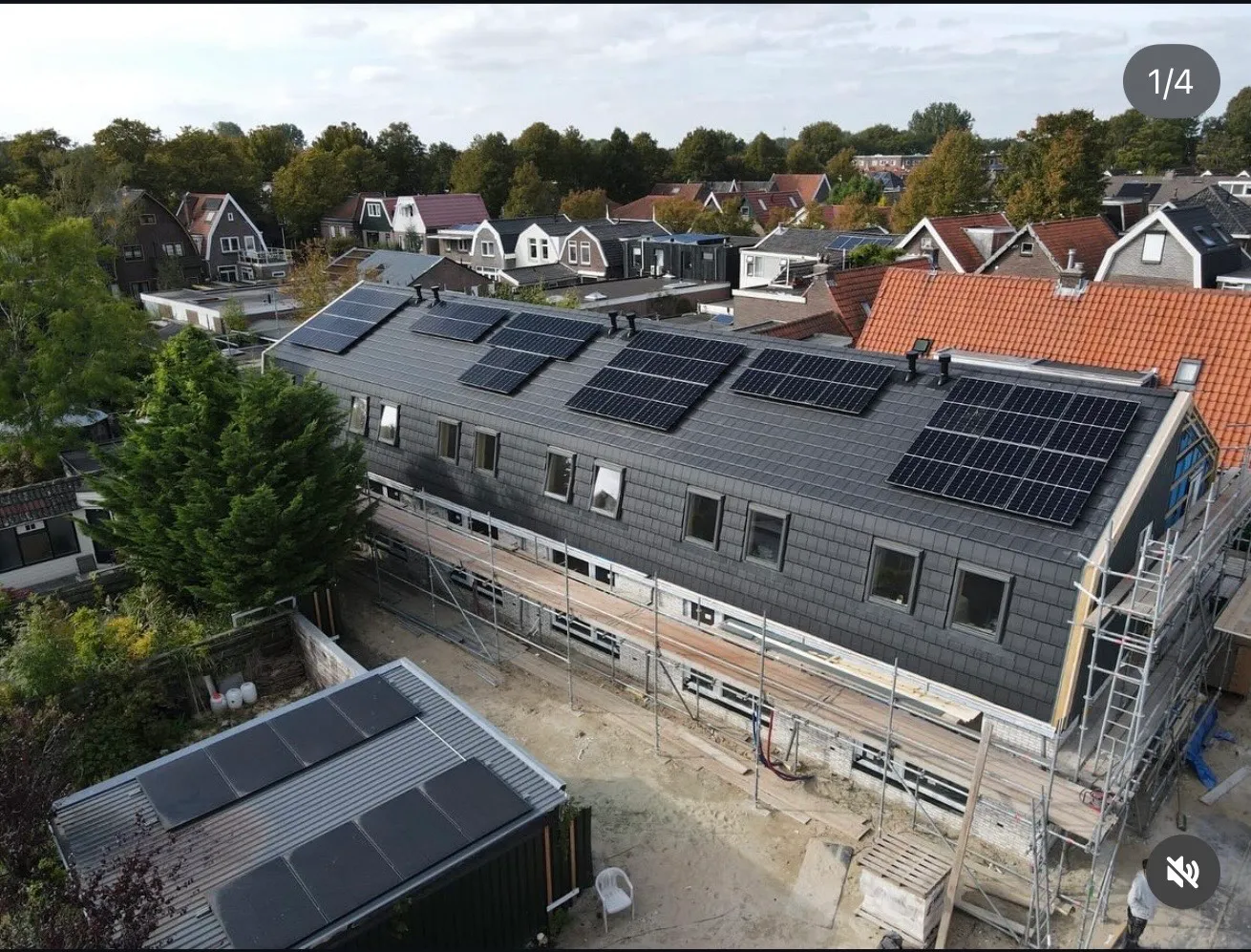 Modern house under construction with solar panels on the roof in a residential neighborhood.