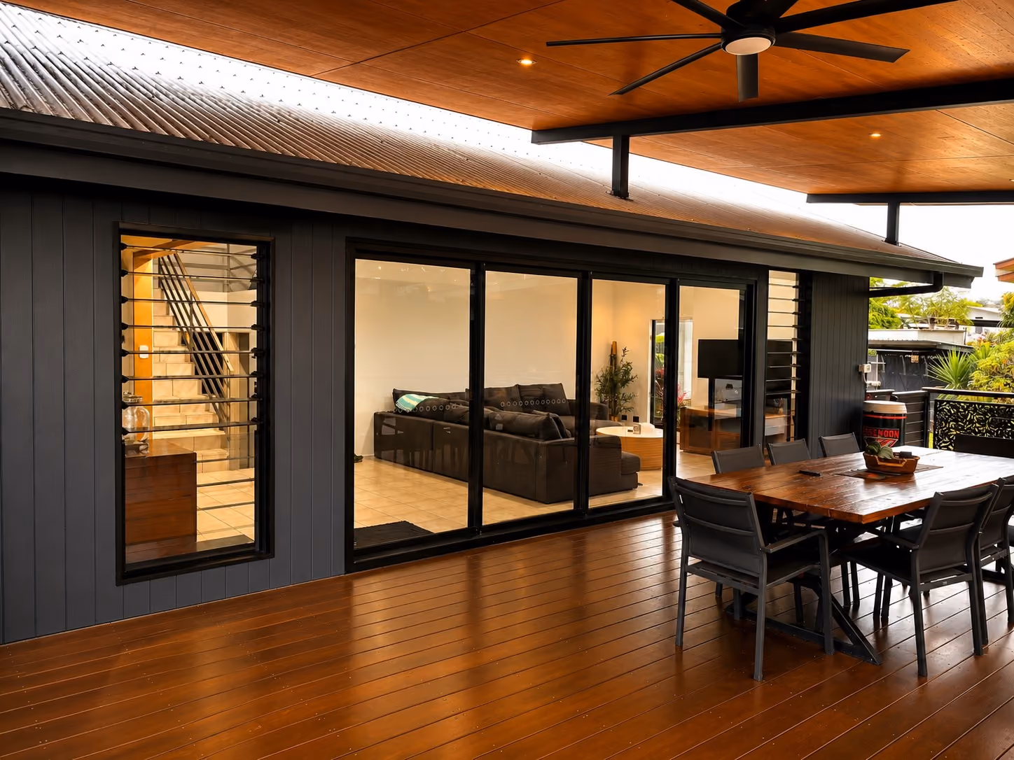 Hardwood timber deck extending from the living room beneath a high outdoor roof.