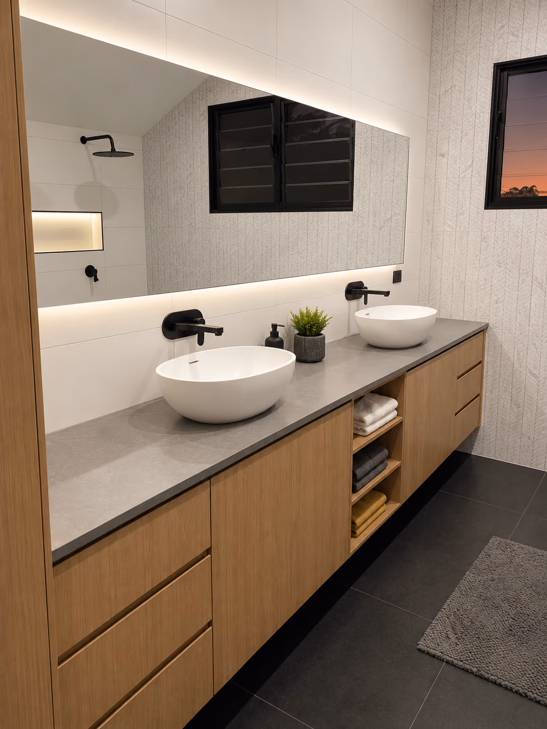 Custom timber double vanity with vessel basins, black tapware, stone benchtop and full-width mirror.