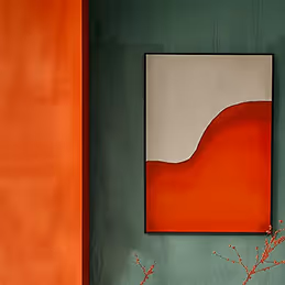 Abstract painting with red and white shapes on green wall next to orange textured surface.