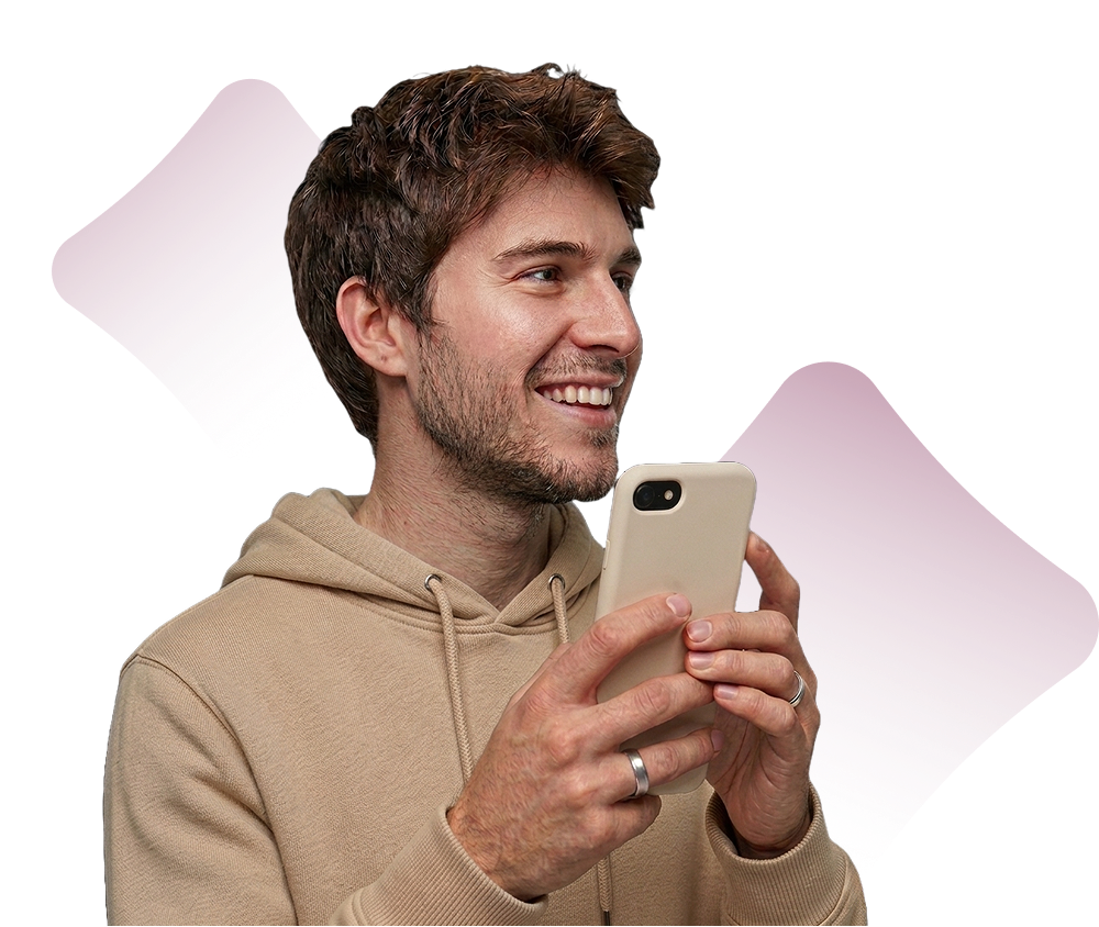 Smiling man in beige hoodie holding smartphone, looking right with purple geometric shapes behind him.