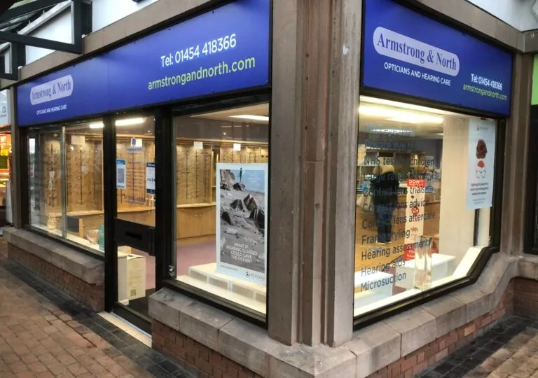 Corner view of Armstrong & North opticians and hearing care shop with blue signage and window displays.