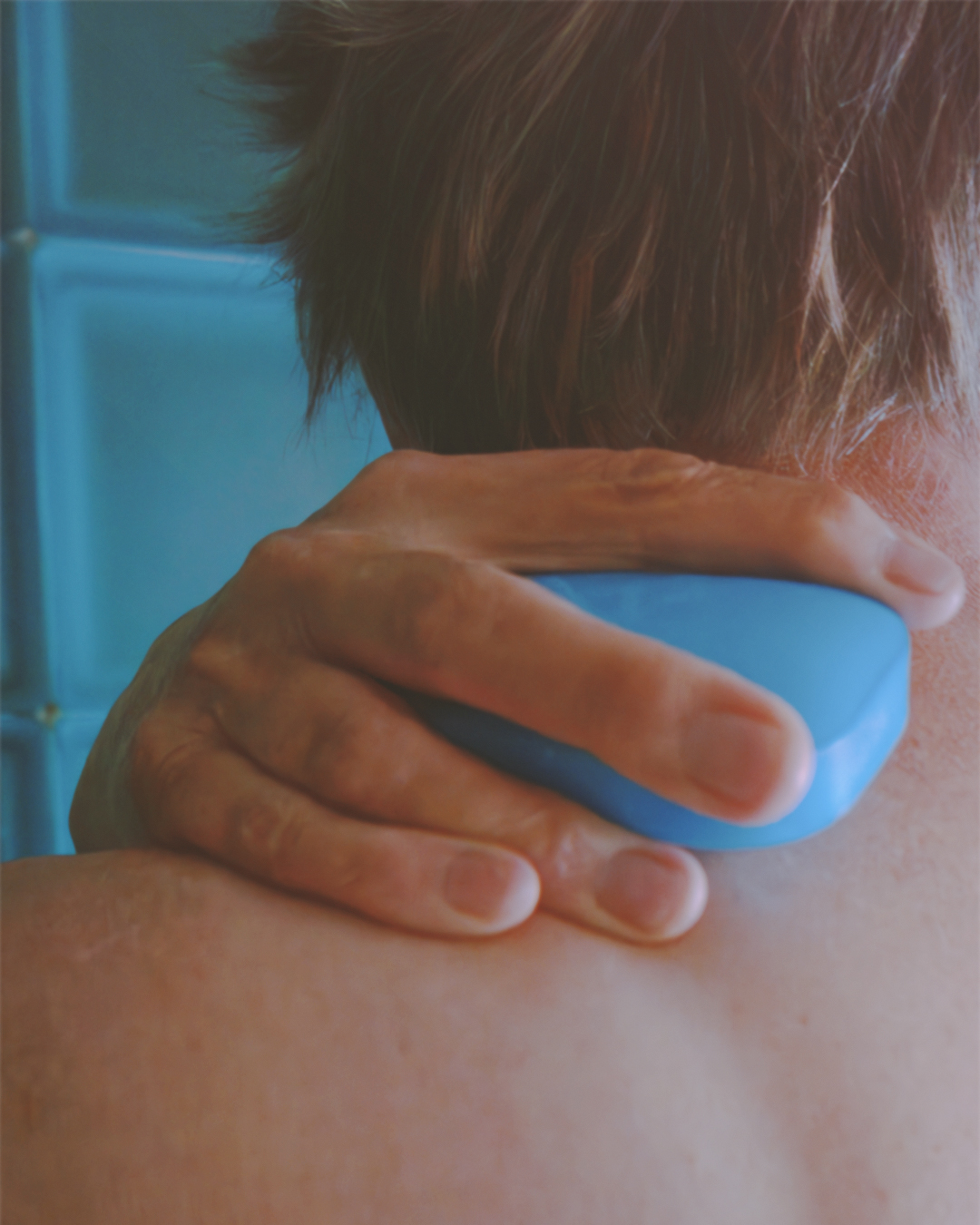 Person holding a blue Eubos soap bar against their neck.