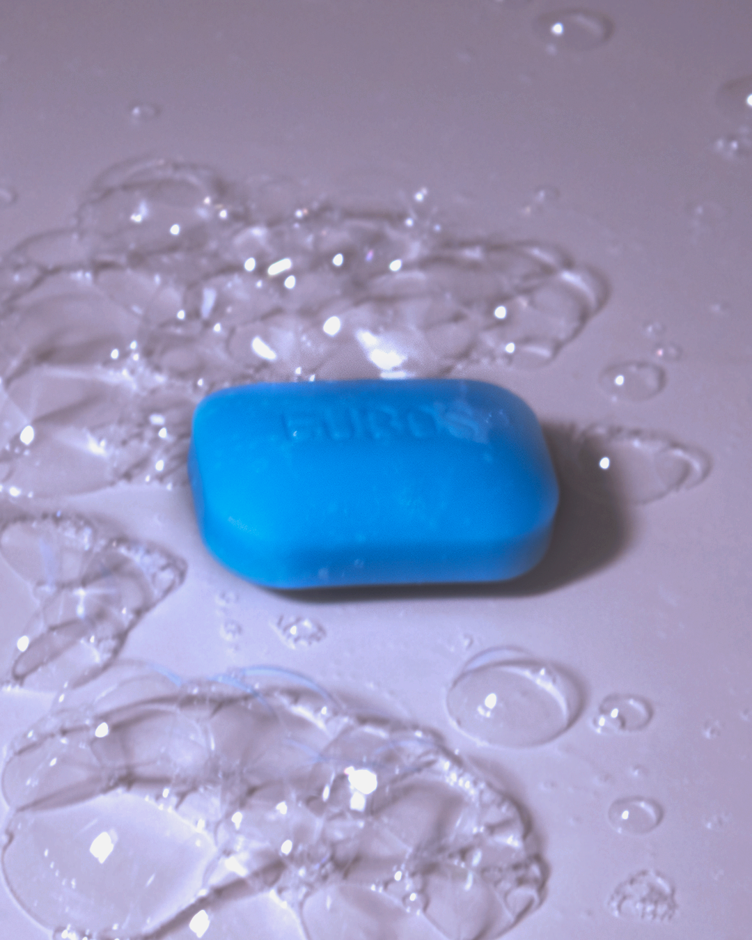 Blue Eubos soap bar surrounded by water bubbles and reflections.