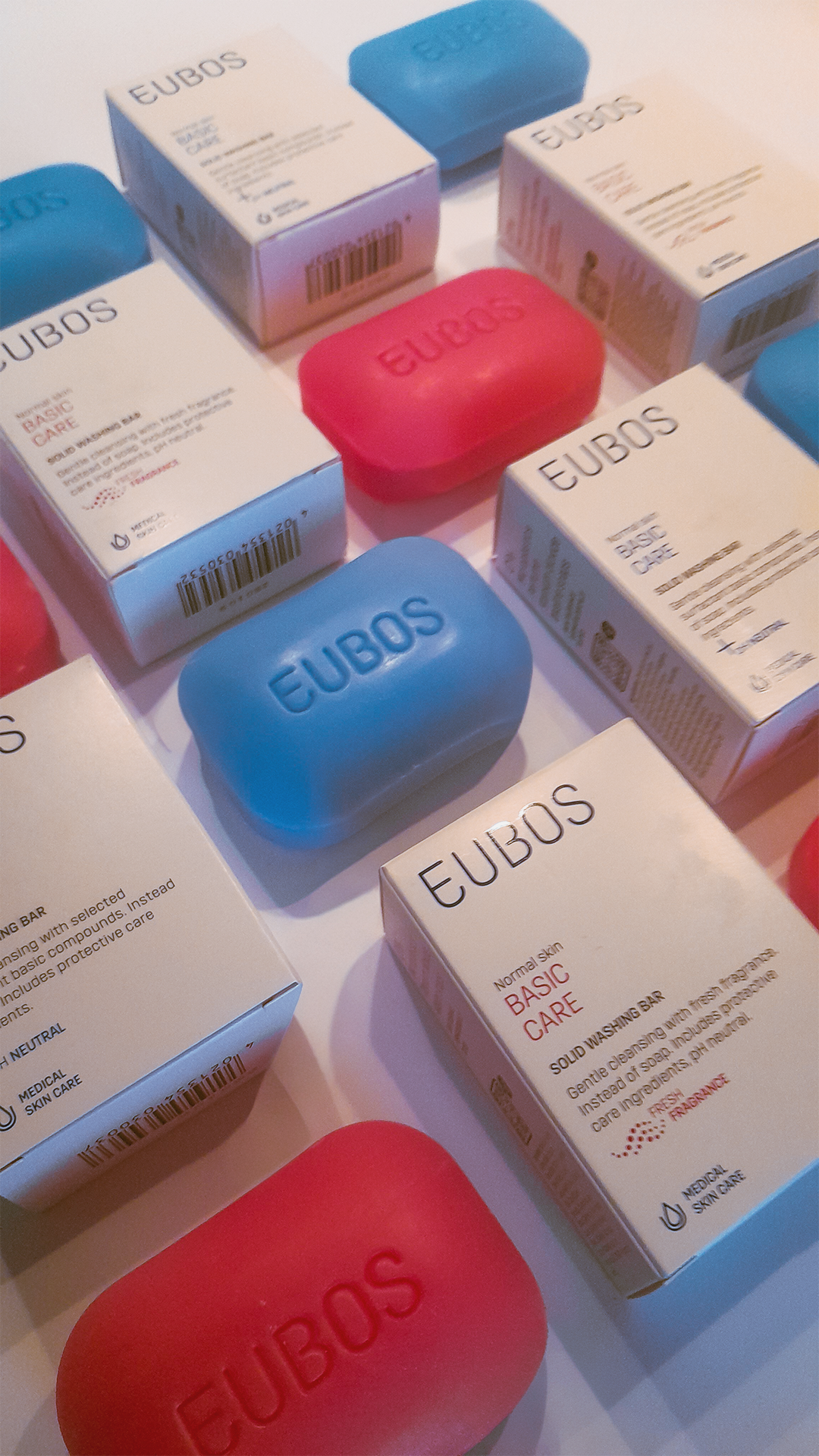 Eubos soap packaging and soap bars arranged in a soft pastel composition.