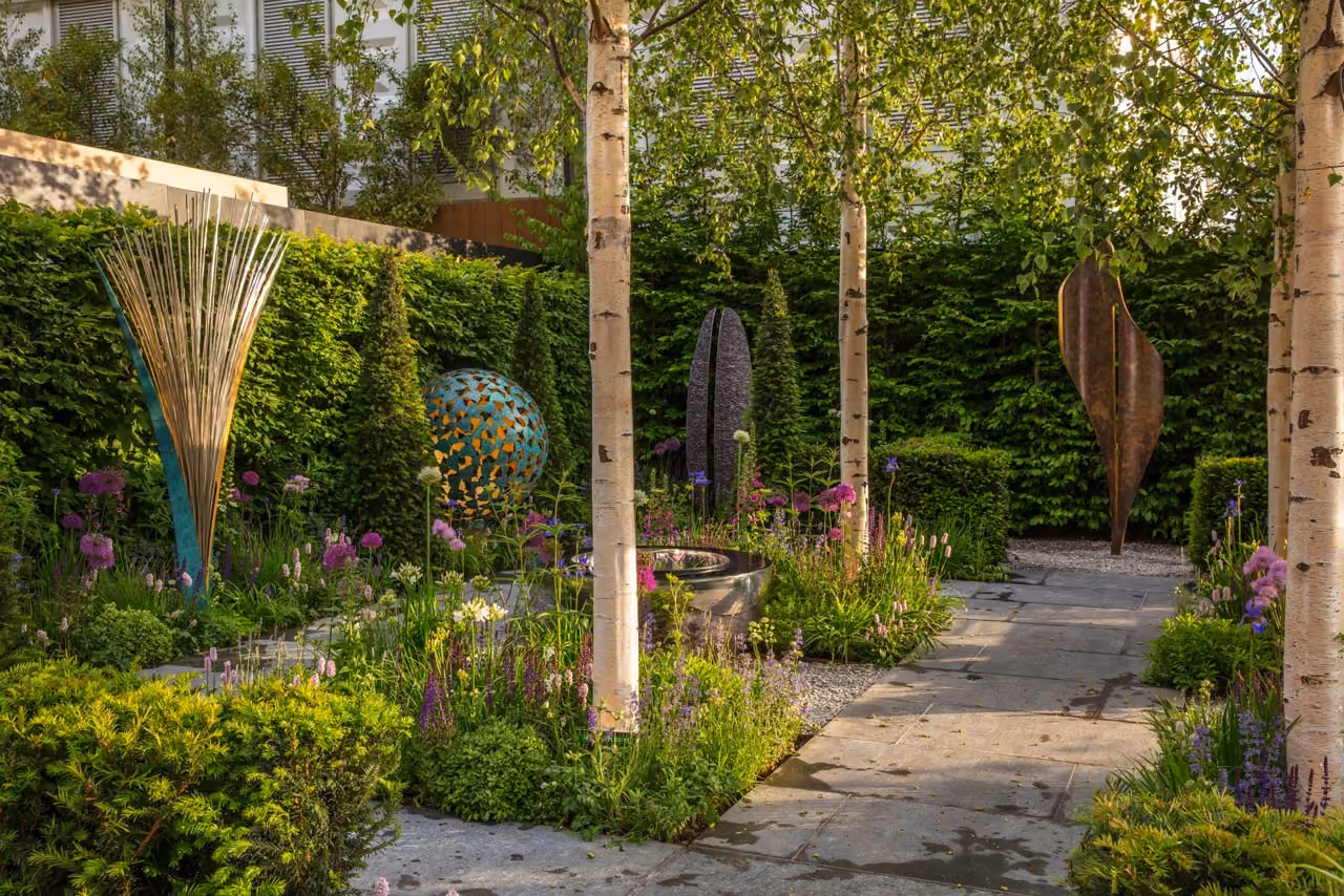 Birch trees, clipped hedging and metal sculptures in a Chelsea Flower Show garden built by Hardwood Landscapes
