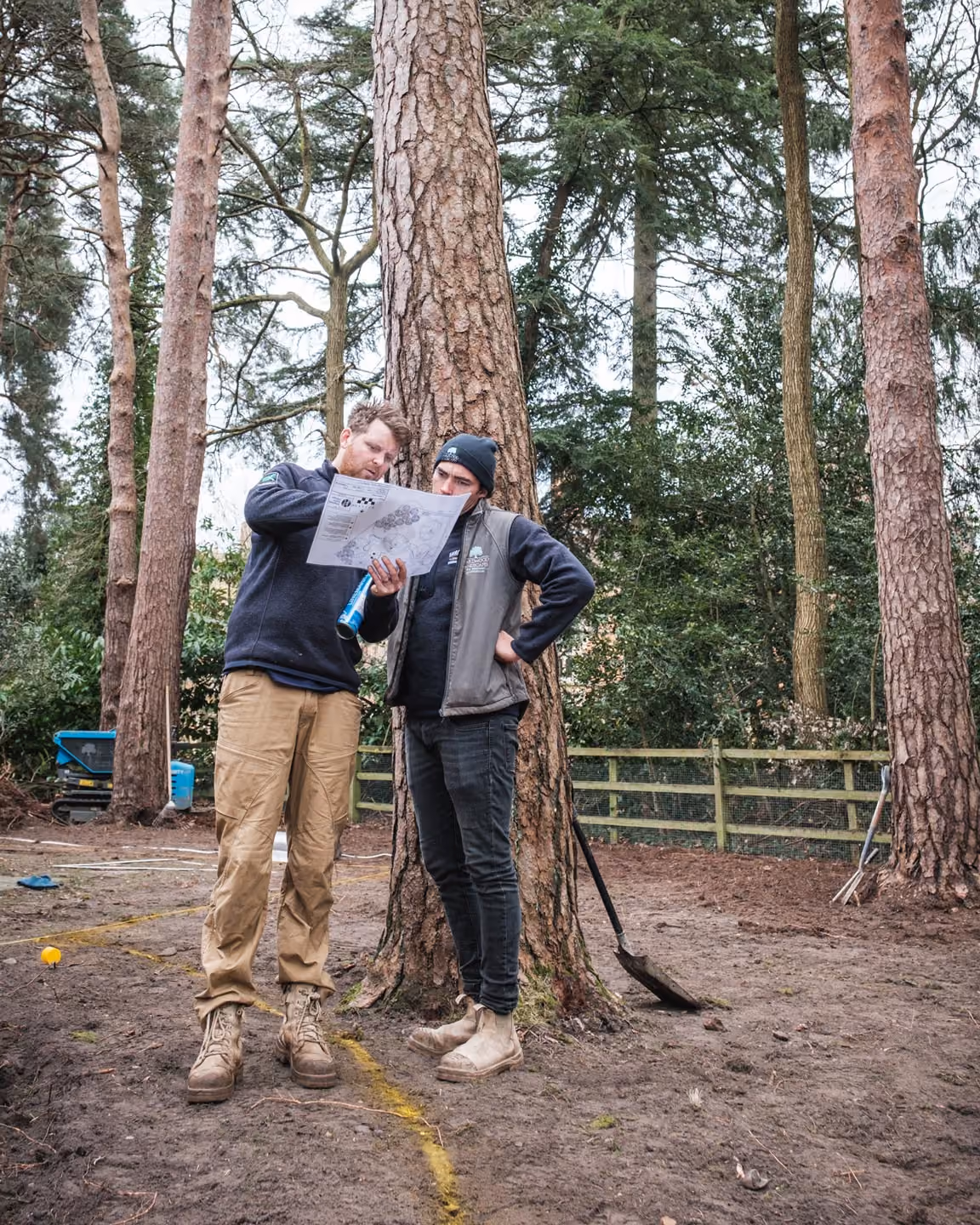 Two Hardwood Landscapes staff reviewing a garden plan on site beneath a mature tree