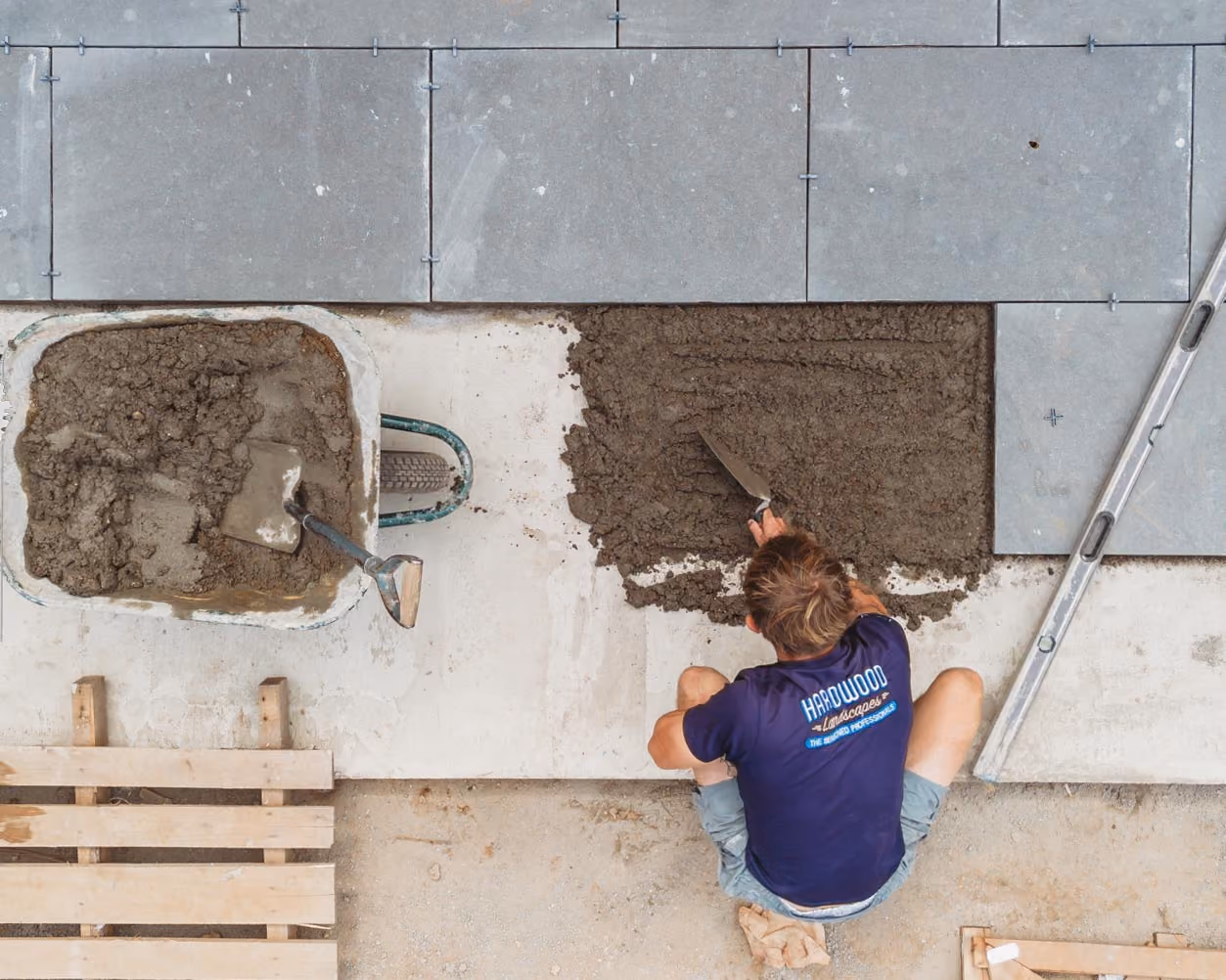 Landscaper bedding stone paving onto mortar with a trowel