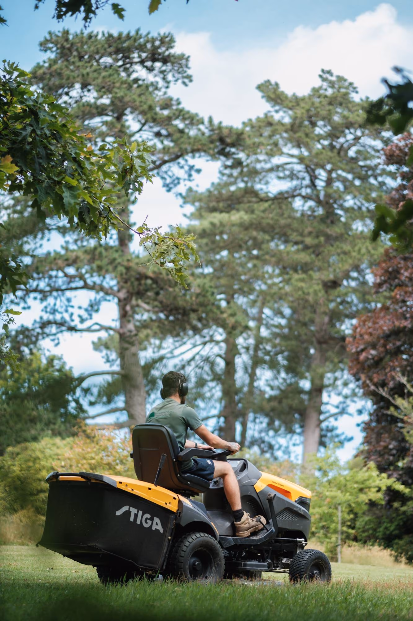 Gardener cutting a large lawn on a ride-on mower