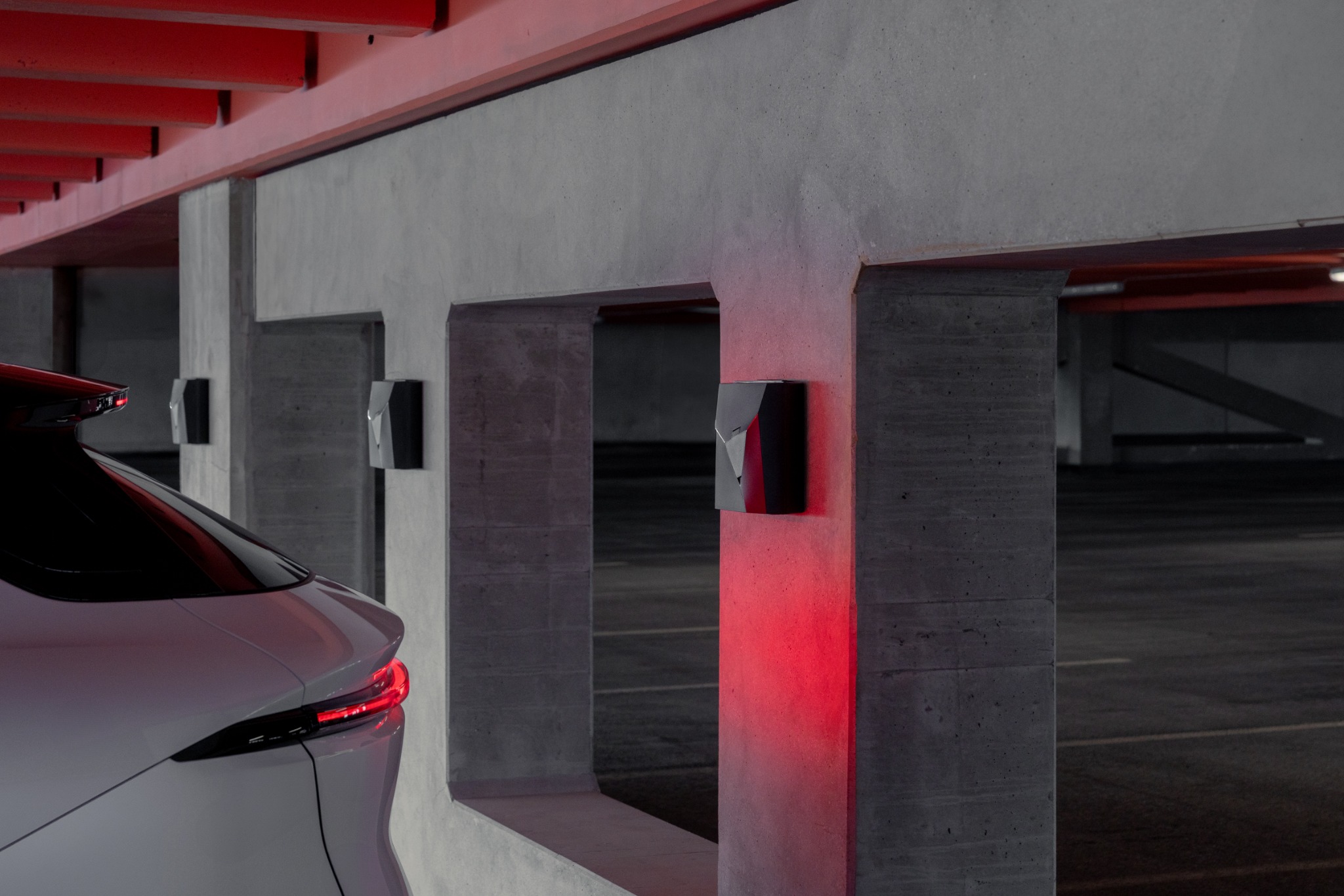 NexBlue-laadpunten aan betonnen wanden bij parkeerplaatsen in een parkeergarage
