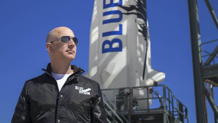 Jeff Bezos standing in front of a Blue Origin rocket.