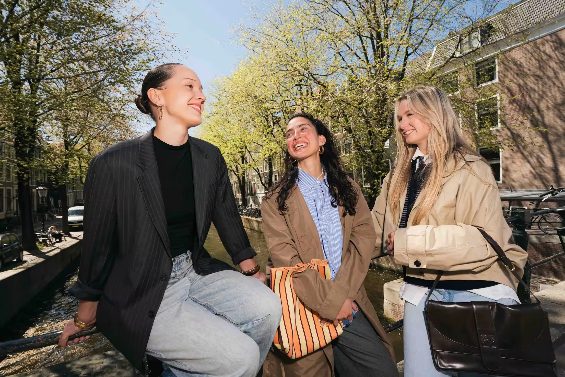 Drie studenten lachen samen aan de gracht