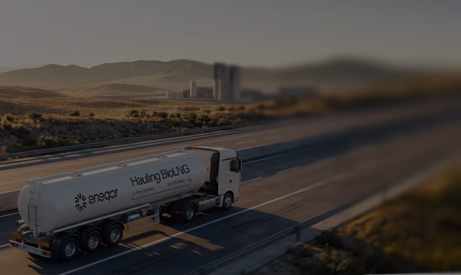White tanker truck labeled 'eneqor Hauling BioLNG from Farmers for HDV fleets' driving on highway.