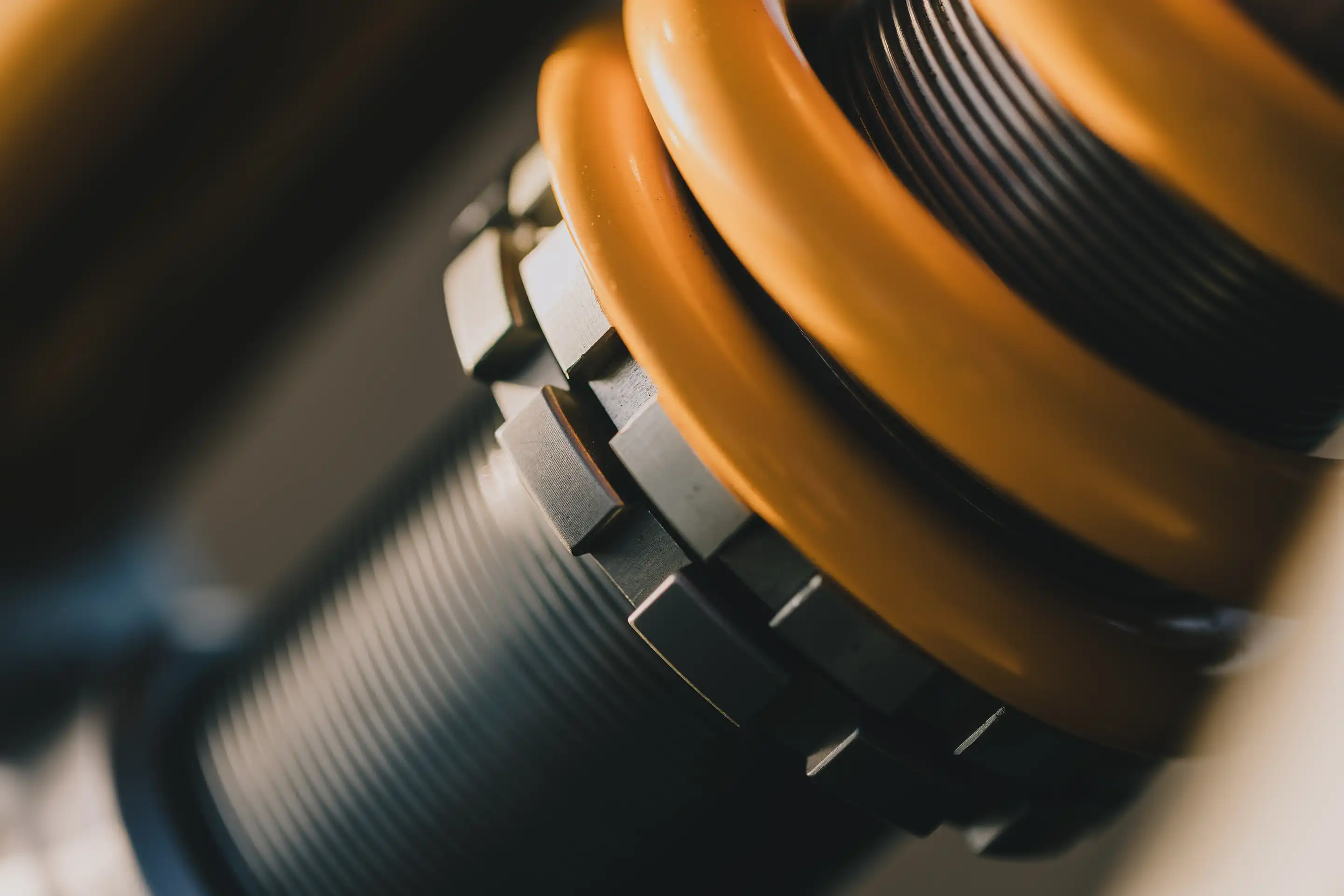 Close-up of a yellow coil spring and threaded metal components of a shock absorber.
