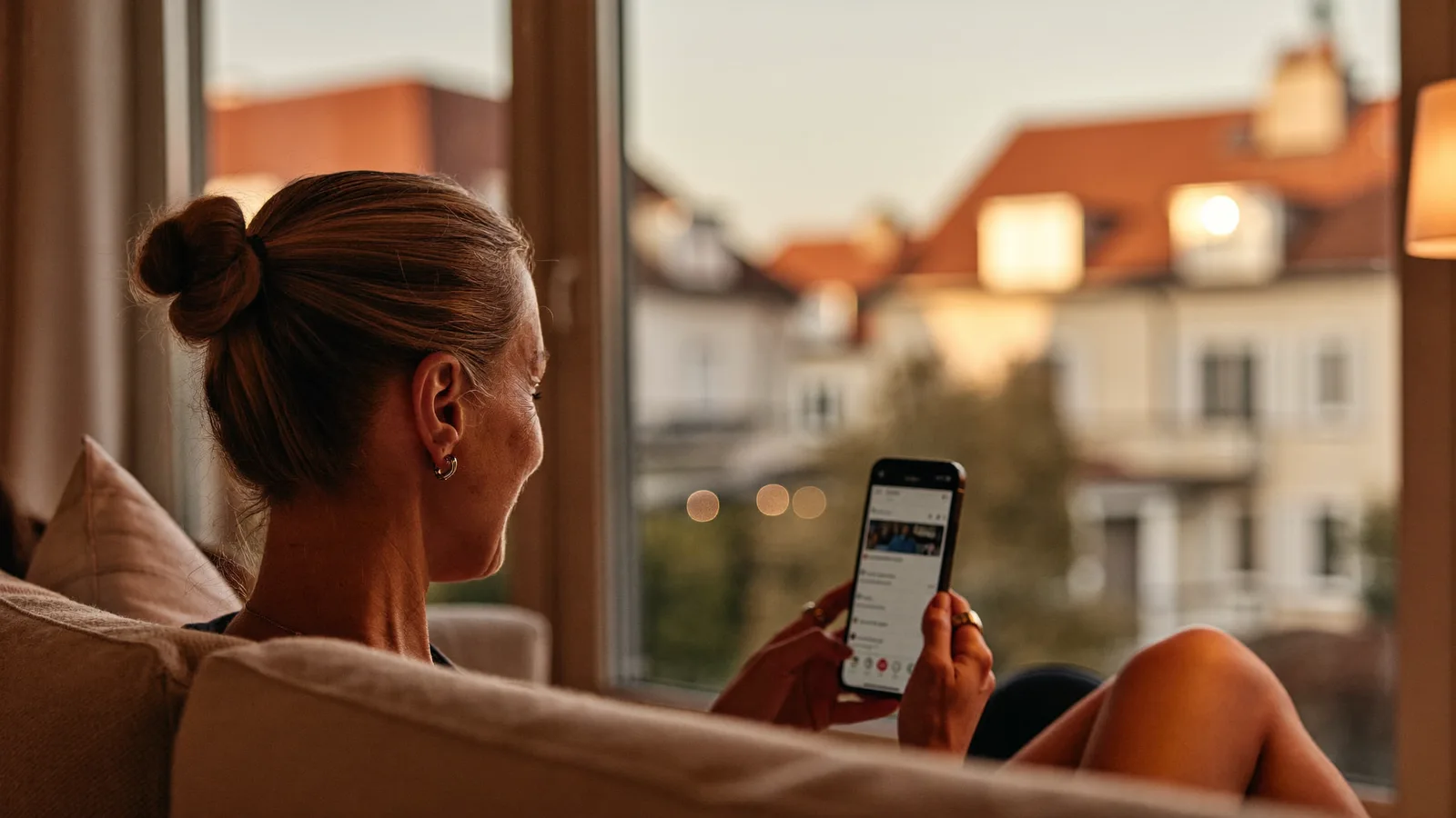 Frau nutzt ihr Smartphone auf dem Sofa – digitale Ansprache von Eigentümern