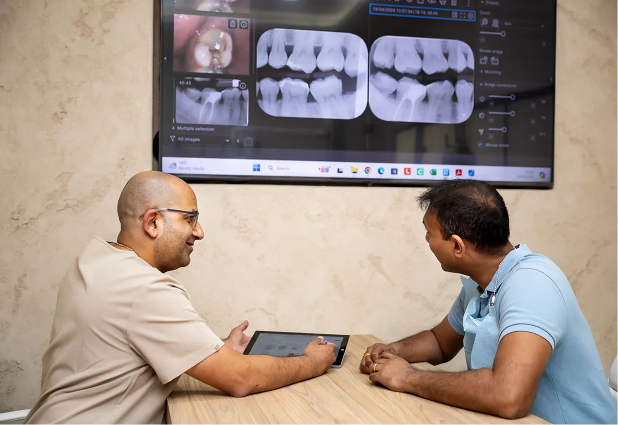 Dentist showing a patient their dental X-rays on a wall-mounted screen