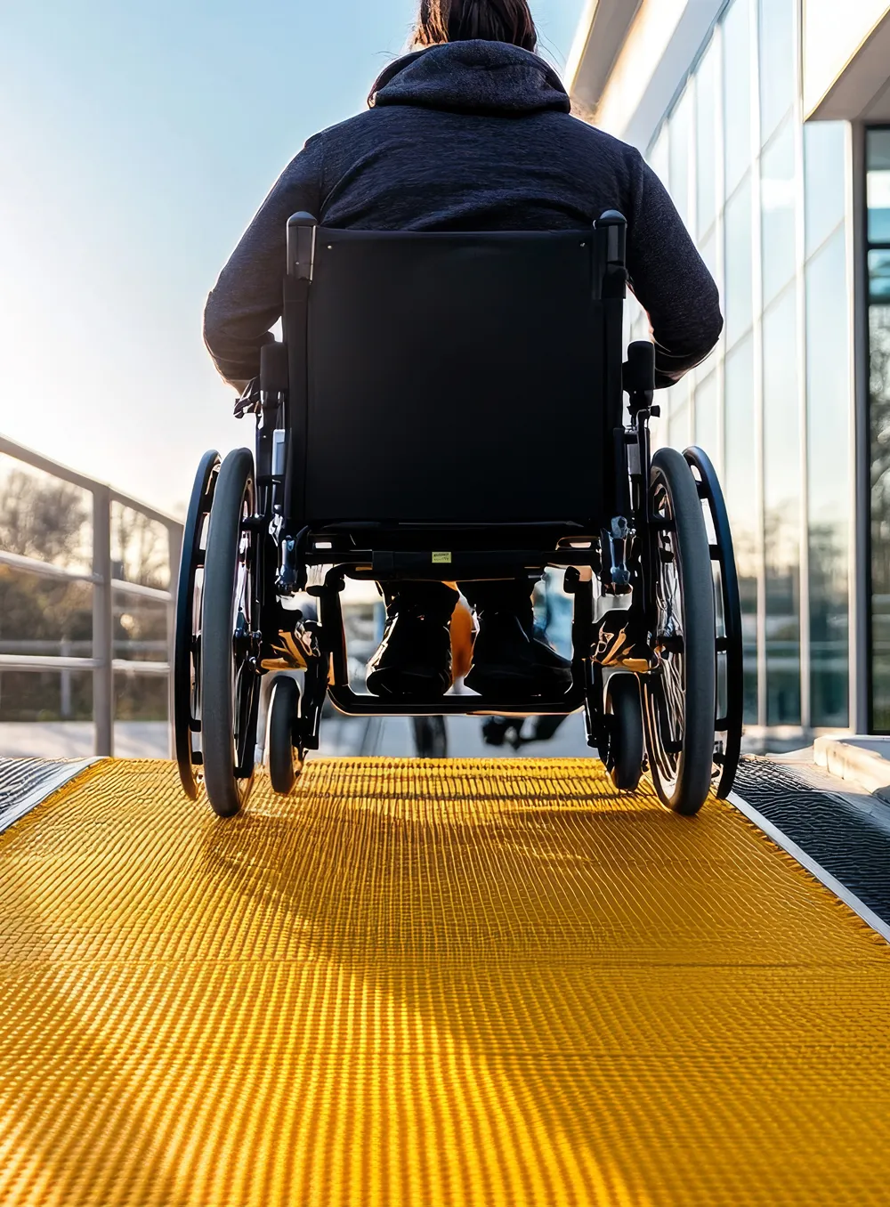 Person in a wheelchair using an accessible ramp outside a building