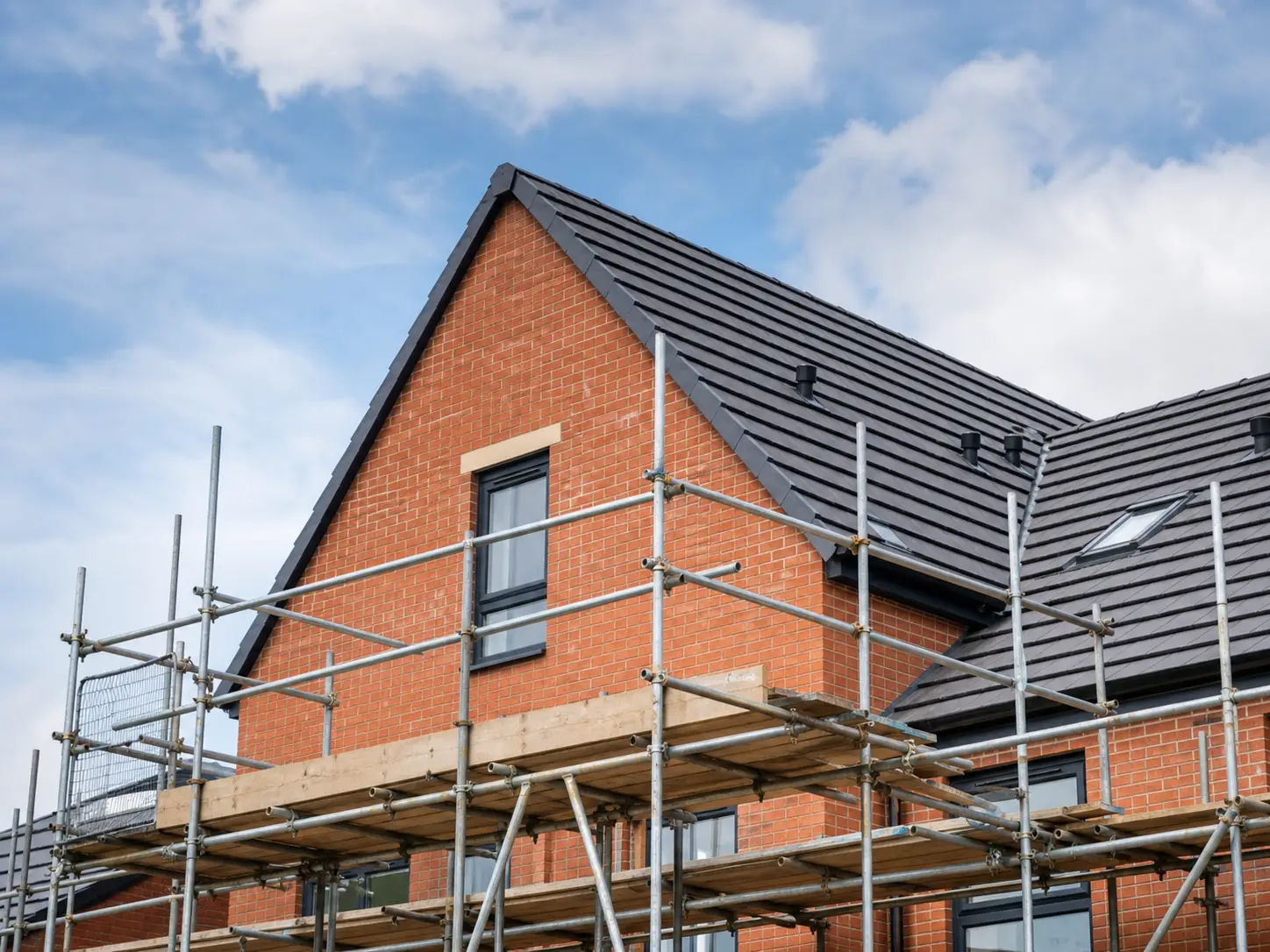 New brick house with scaffold during roofing works