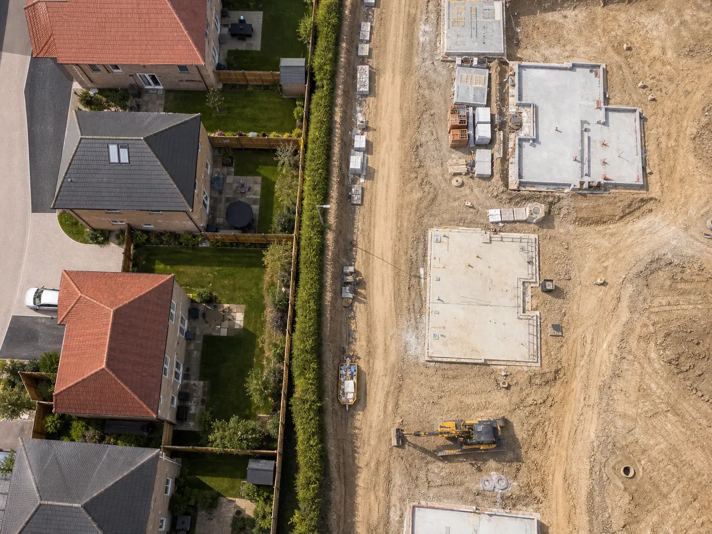 Aerial view of house foundations beside an existing housing estate