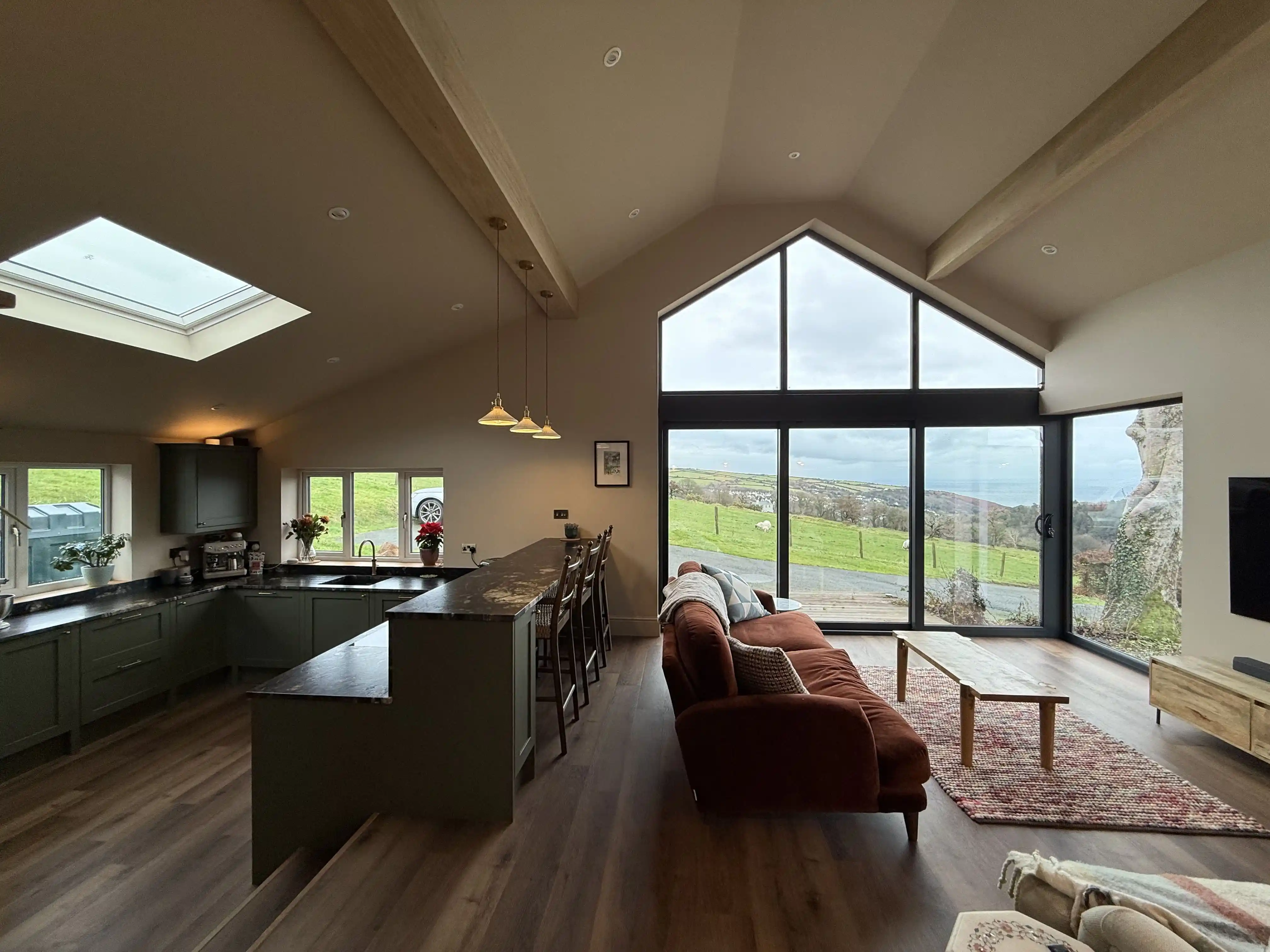 Open-plan kitchen and living space with vaulted ceiling and gable glazing at Ballamillighyn Cottage, Laxey