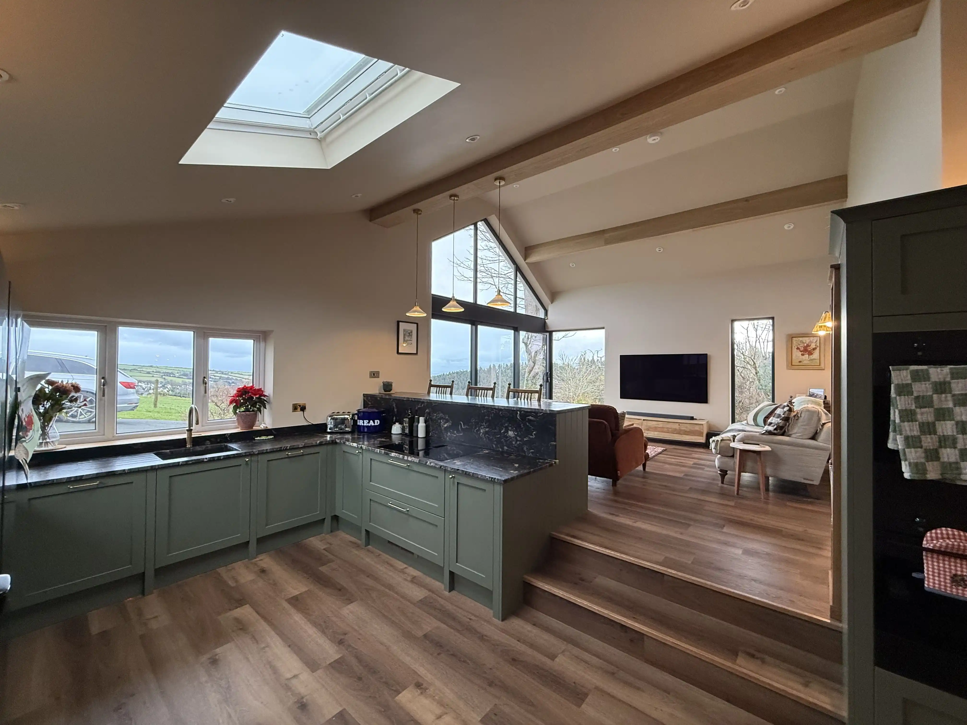 Open-plan kitchen with rooflight and green units at Ballamillighyn Cottage, Laxey