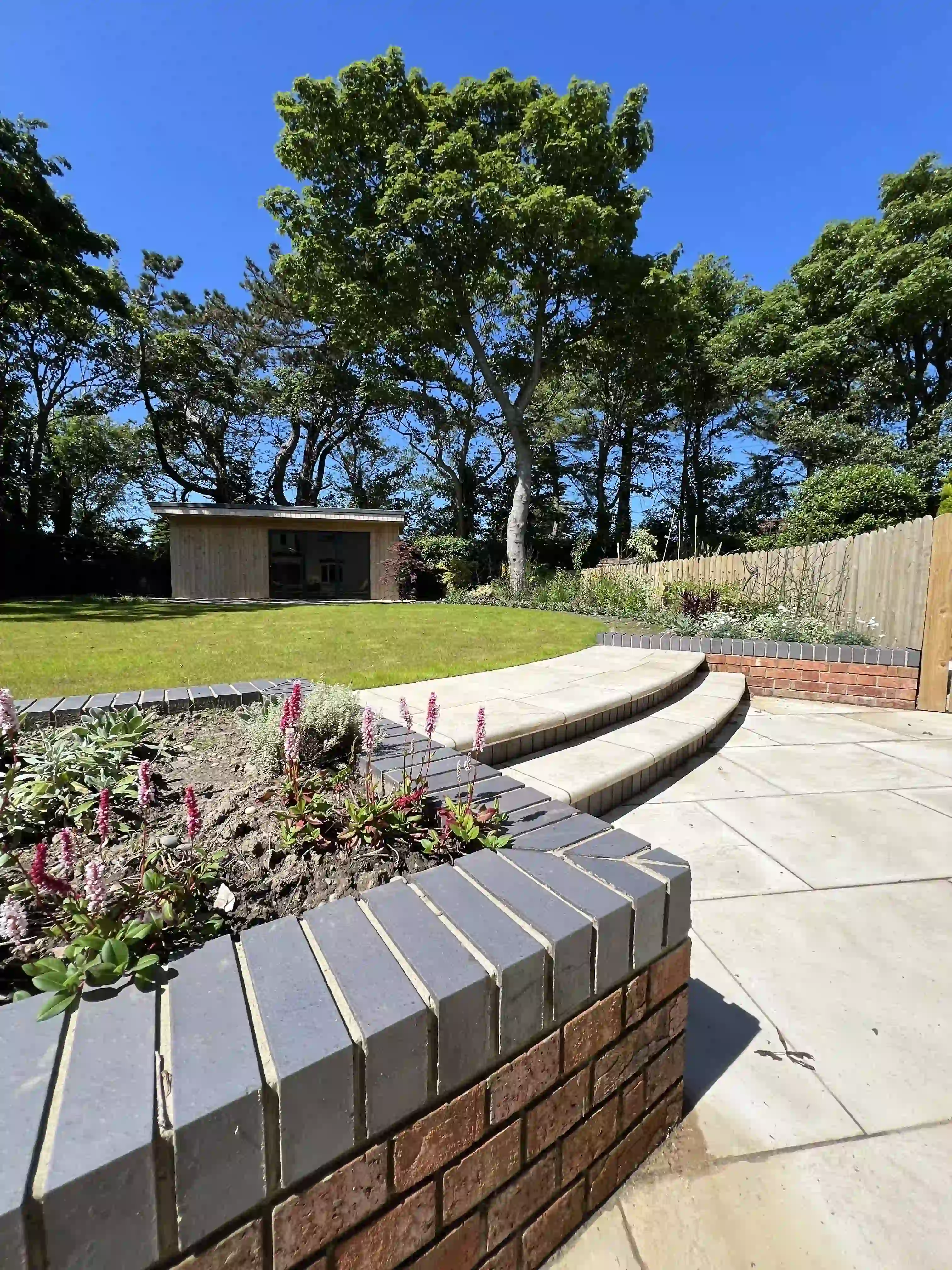 Raised brick planter and curved steps to the lawn and garden room at 15 The Links, Peel