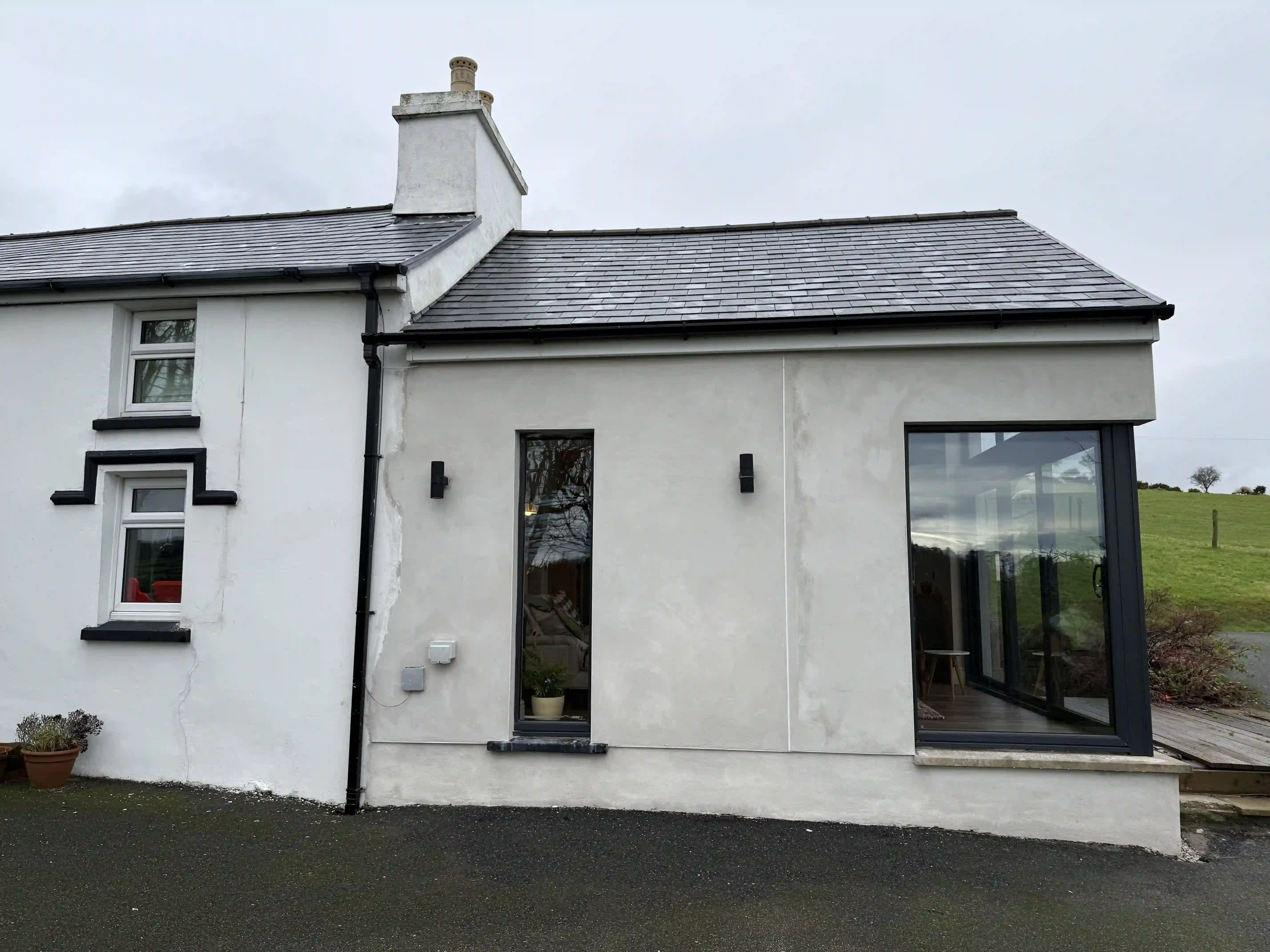 Rendered cottage elevation with new corner glazing at Ballamillighyn Cottage, Laxey
