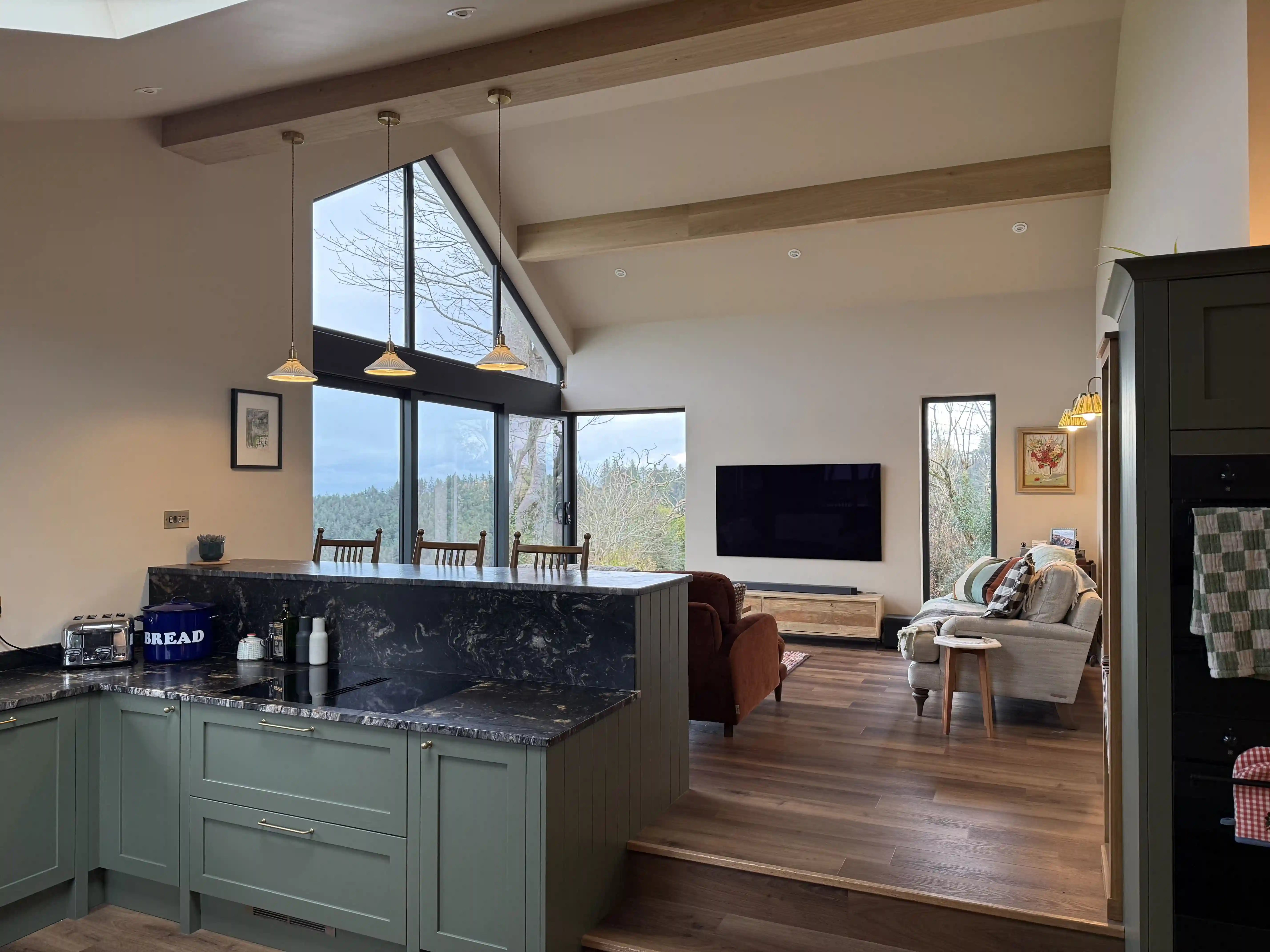 Open-plan kitchen and living space with vaulted ceiling and gable glazing at Ballamillighyn Cottage, Laxey
