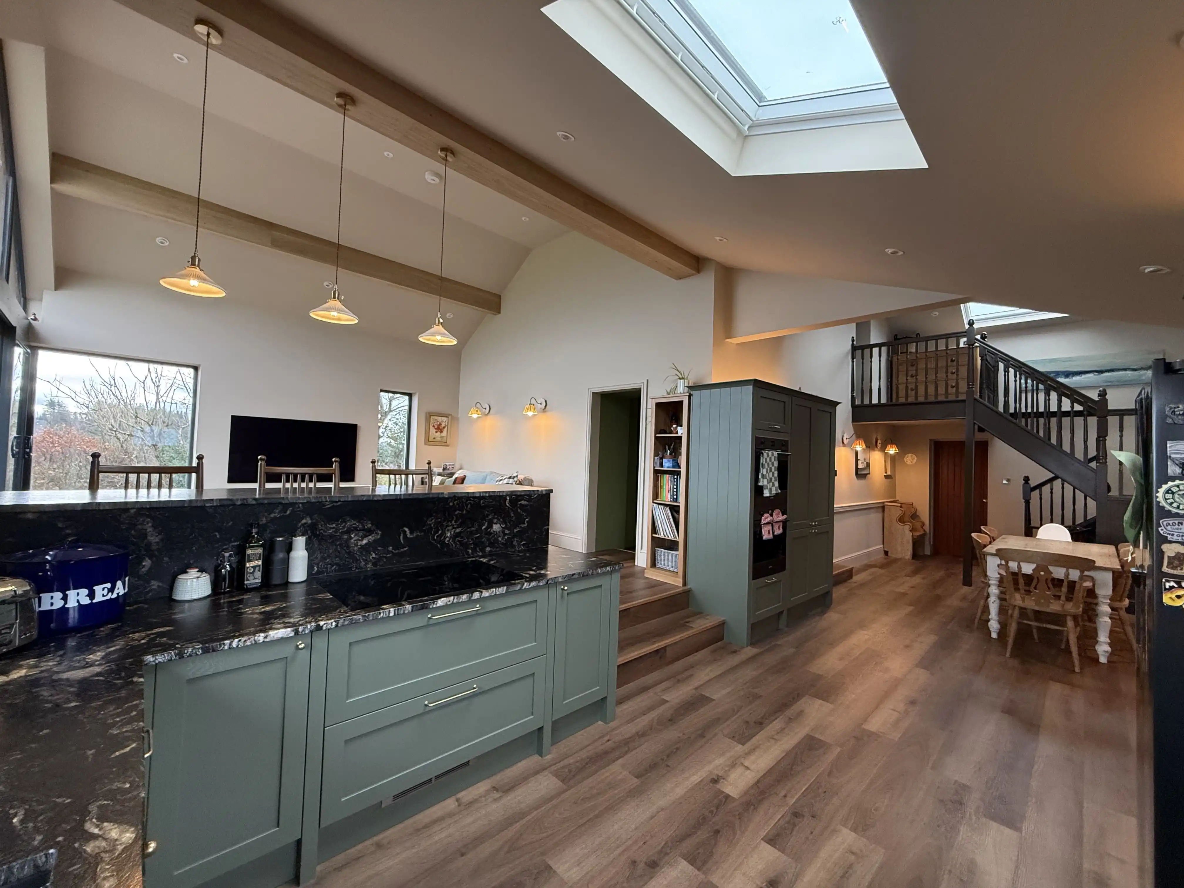 Kitchen with green shaker units, rooflight and staircase at Ballamillighyn Cottage, Laxey