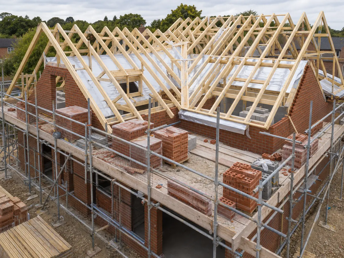Timber roof trusses on a brick house under construction with scaffold
