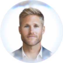 Portrait of a blond man with blue eyes wearing a white shirt and blazer with soft lighting.