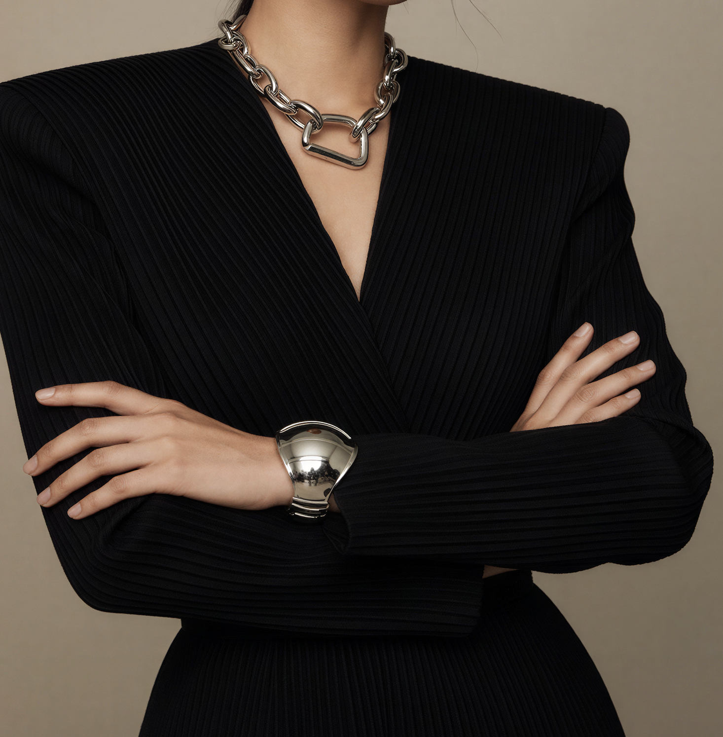 Woman with her arms crossed wearing silver jewelry with a  black outfit