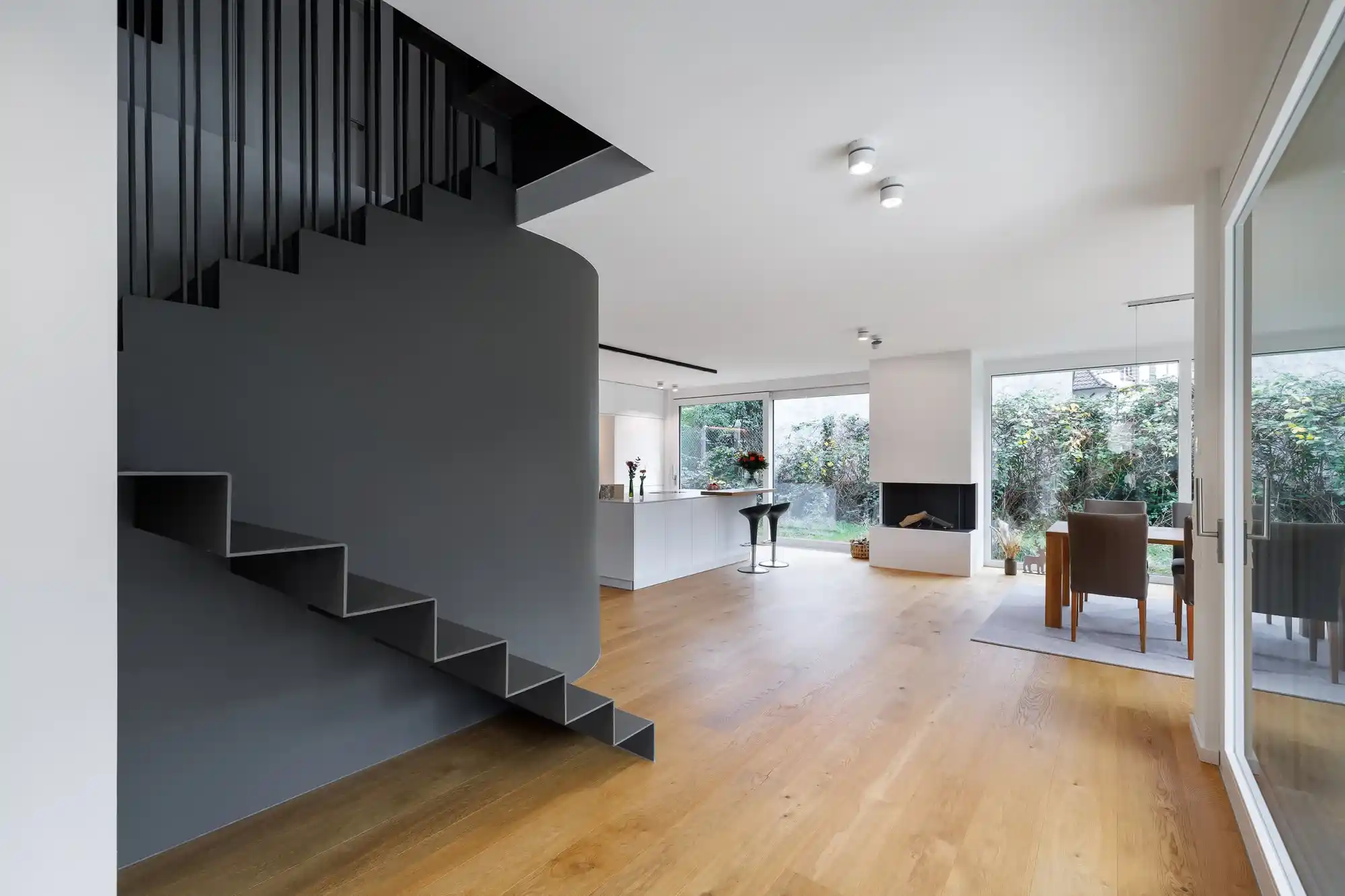 Offener Wohnraum mit schwarzer Stahltreppe und Holzboden