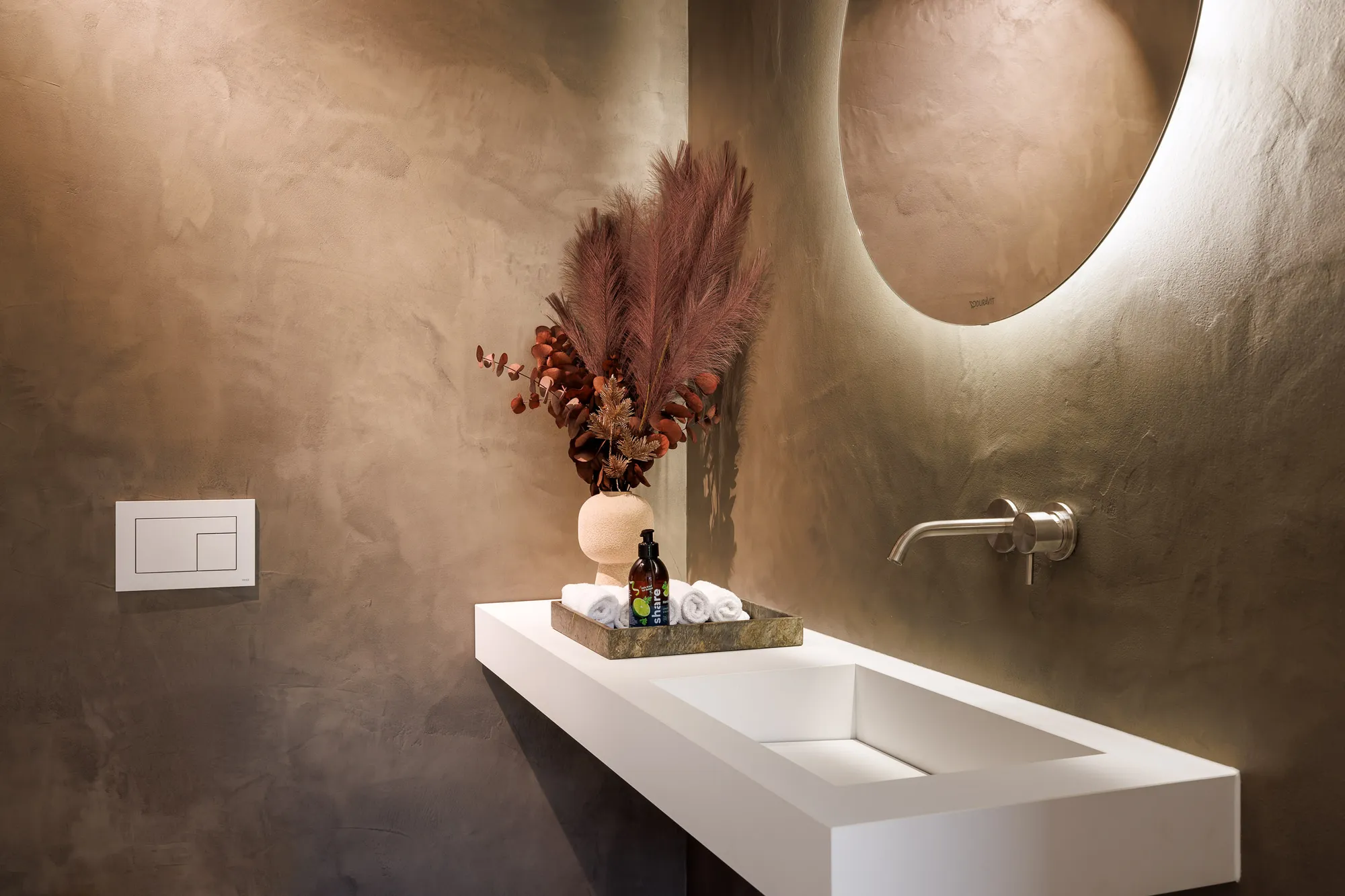 Gäste-WC mit warm getönter Spachtelwand, weißem Aufsatzwaschbecken und Trockenblumen