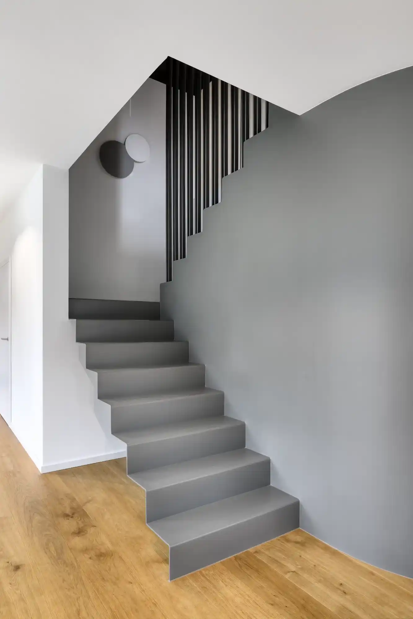 Grau lackierte Treppe mit schwarzem Lamellengeländer