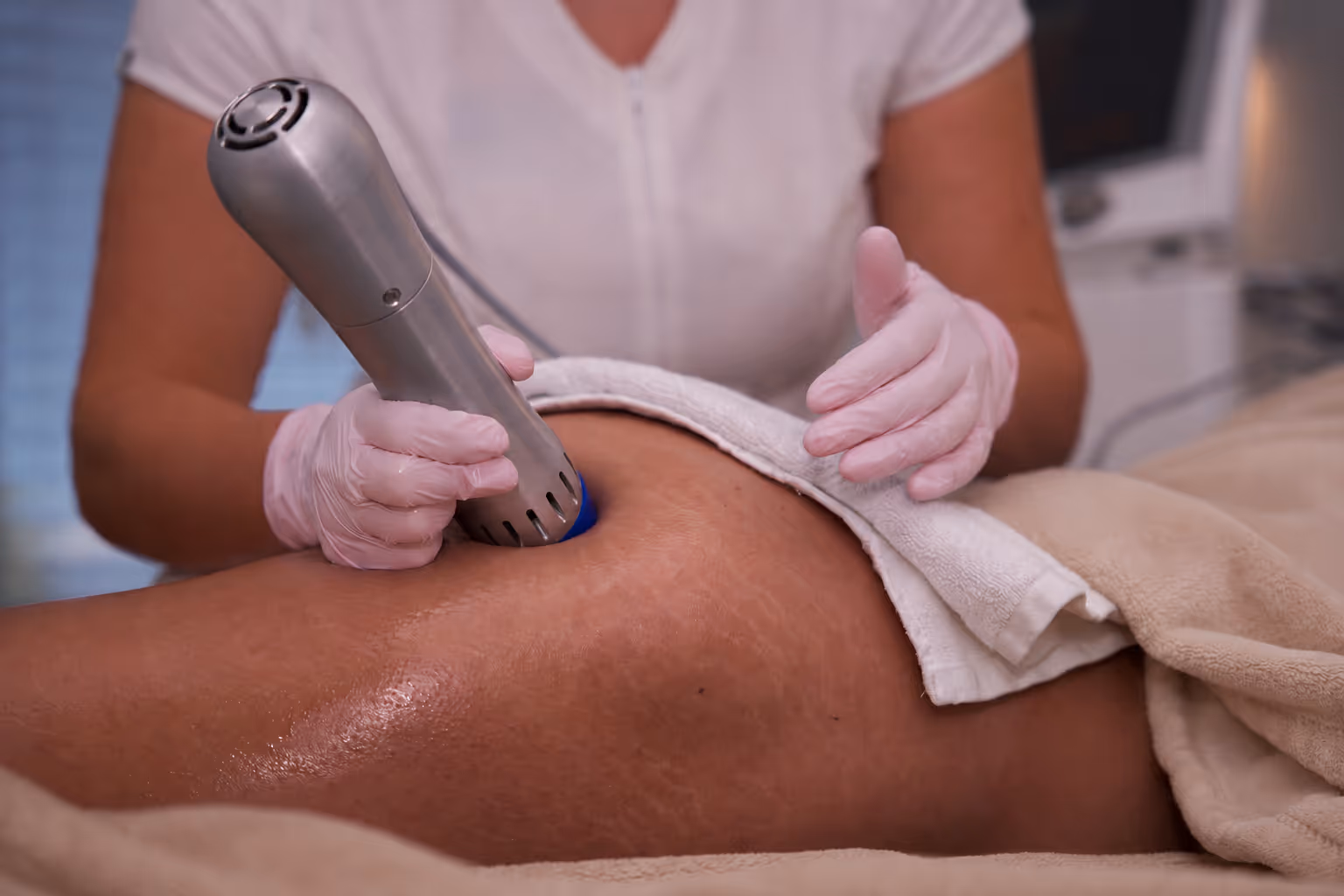 Kosmetikerin führt eine Ultraschall- oder Laserbehandlung am Oberschenkel eines Kunden durch.
