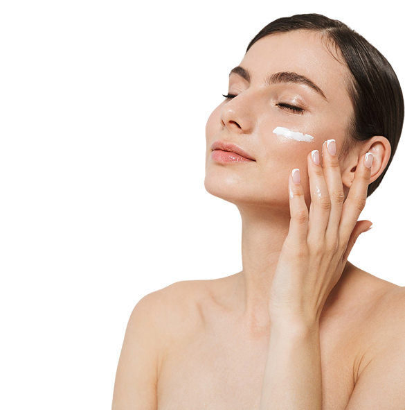 Young woman with eyes closed applying cream to her cheek with her fingers.