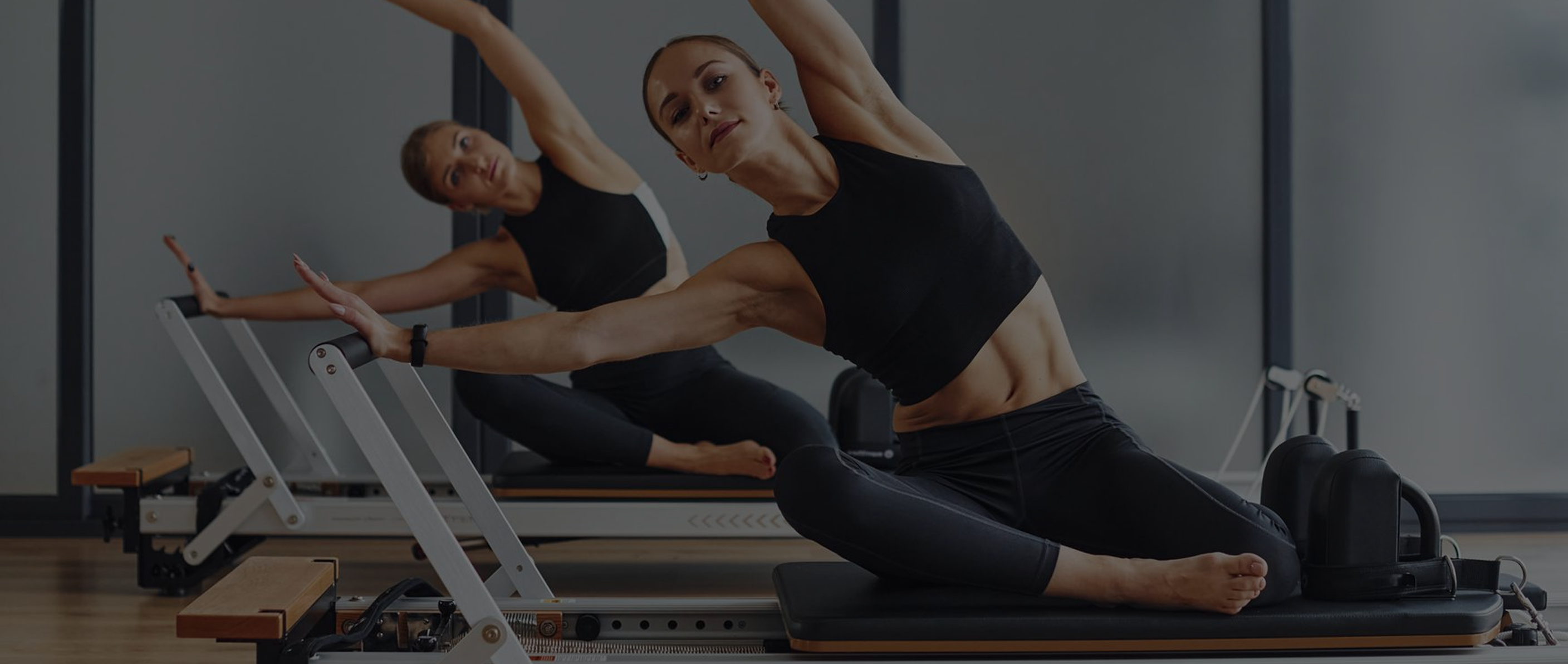 Woman in white sportswear performing a challenging yoga arm balance pose indoors on a mat.