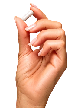 Hand with manicured nails holding a white capsule pill between thumb and forefinger.