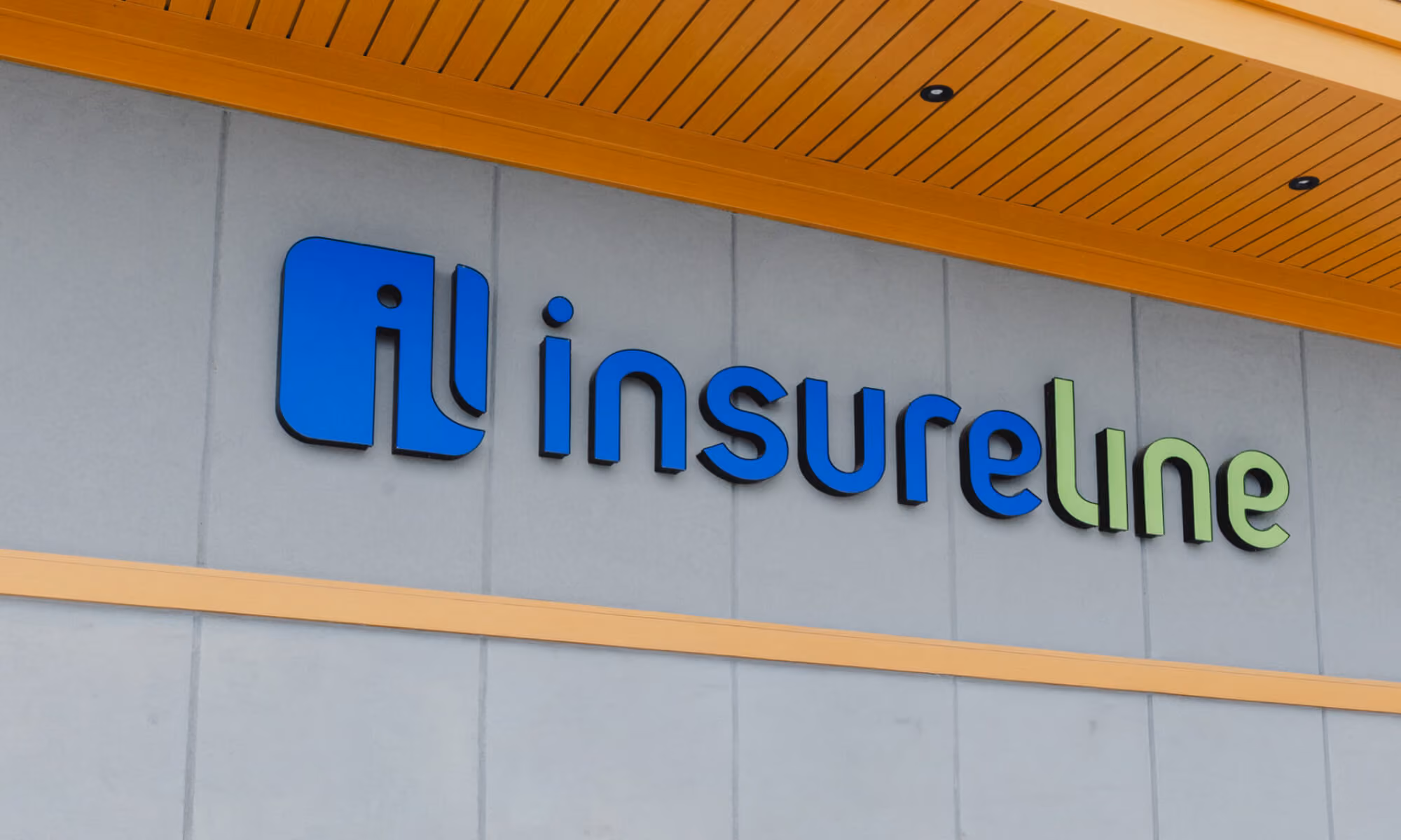 Insureline company sign on a building exterior wall with blue and green lettering.