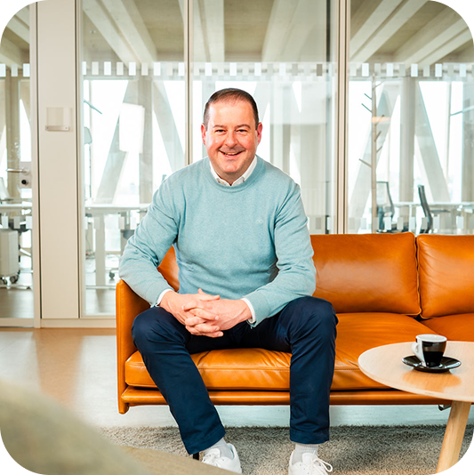 Christian Oberle sitzt auf einem orangefarbenen Sofa im Büro.