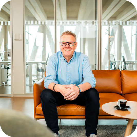 Udo Blank sitzt auf einem orangefarbenen Sofa im Büro.